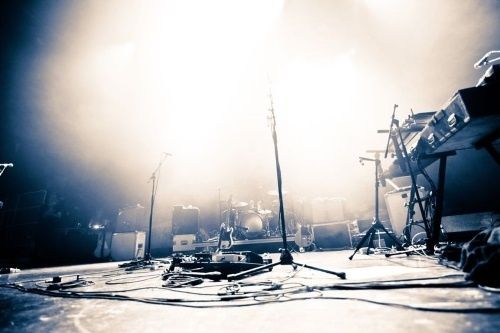 Podium met verspreide audiokabels, microfoonstatieven en muziekapparatuur