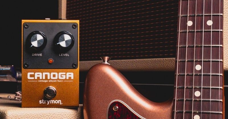 Strymon Canoga-fuzzpedaal naast een elektrische gitaar en versterker